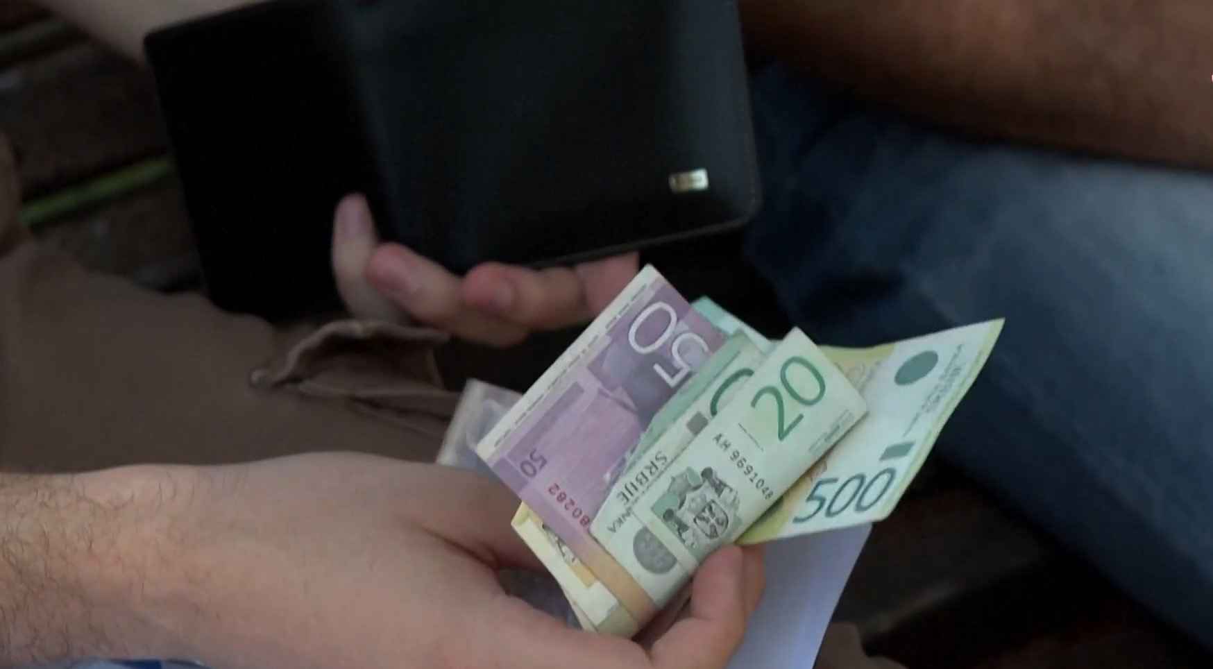 Osoba drži papirni novac u rukama ispred novčanika